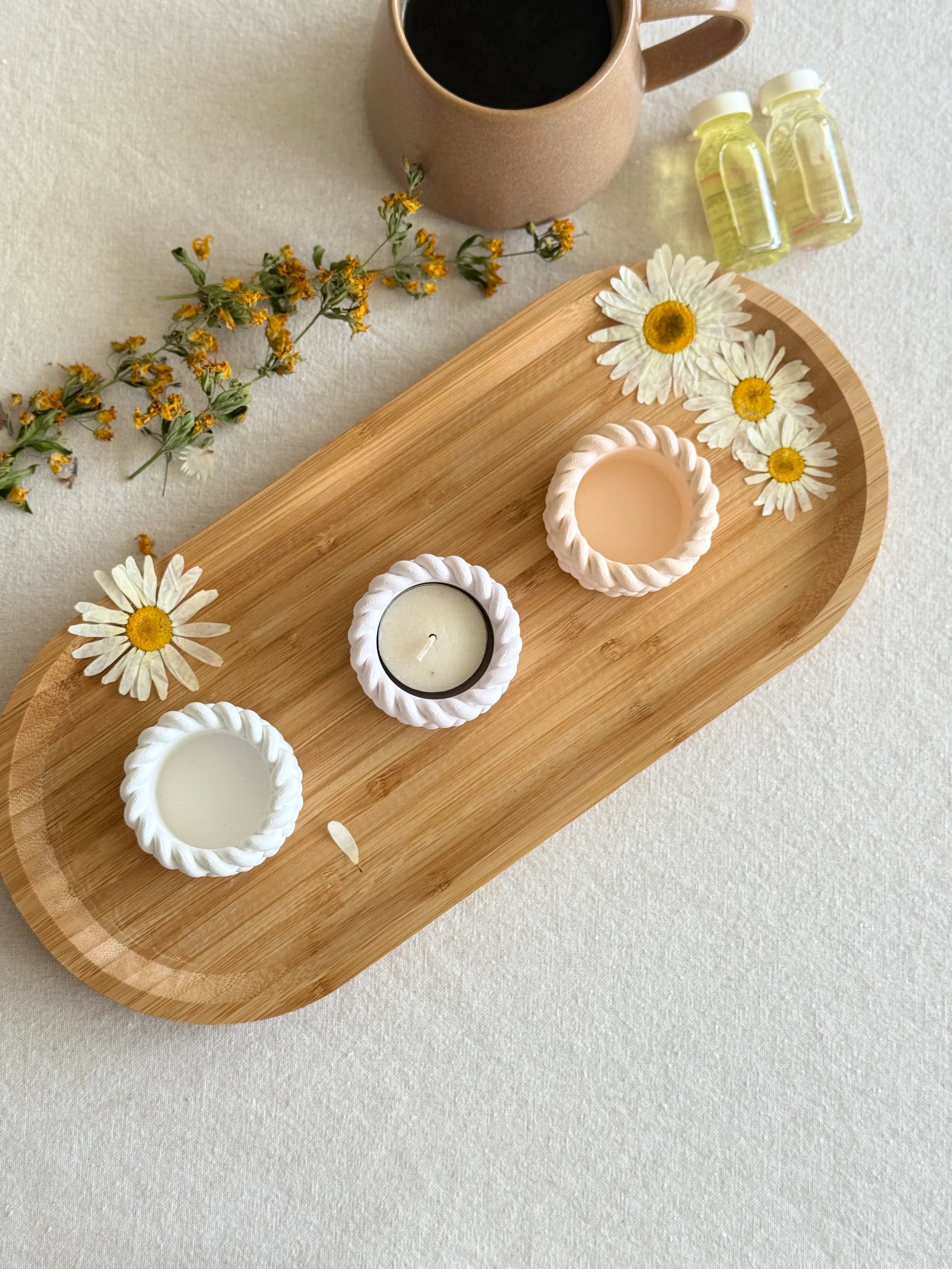 Handmade soy candles in rope-textured holders on a bamboo tray with daisies, styled for cozy Scandinavian home décor.