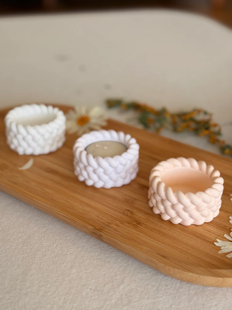 Handmade ceramic candle holders with braided texture in white and blush, styled on wooden tray with dried flowers for cozy Scandinavian home decor.