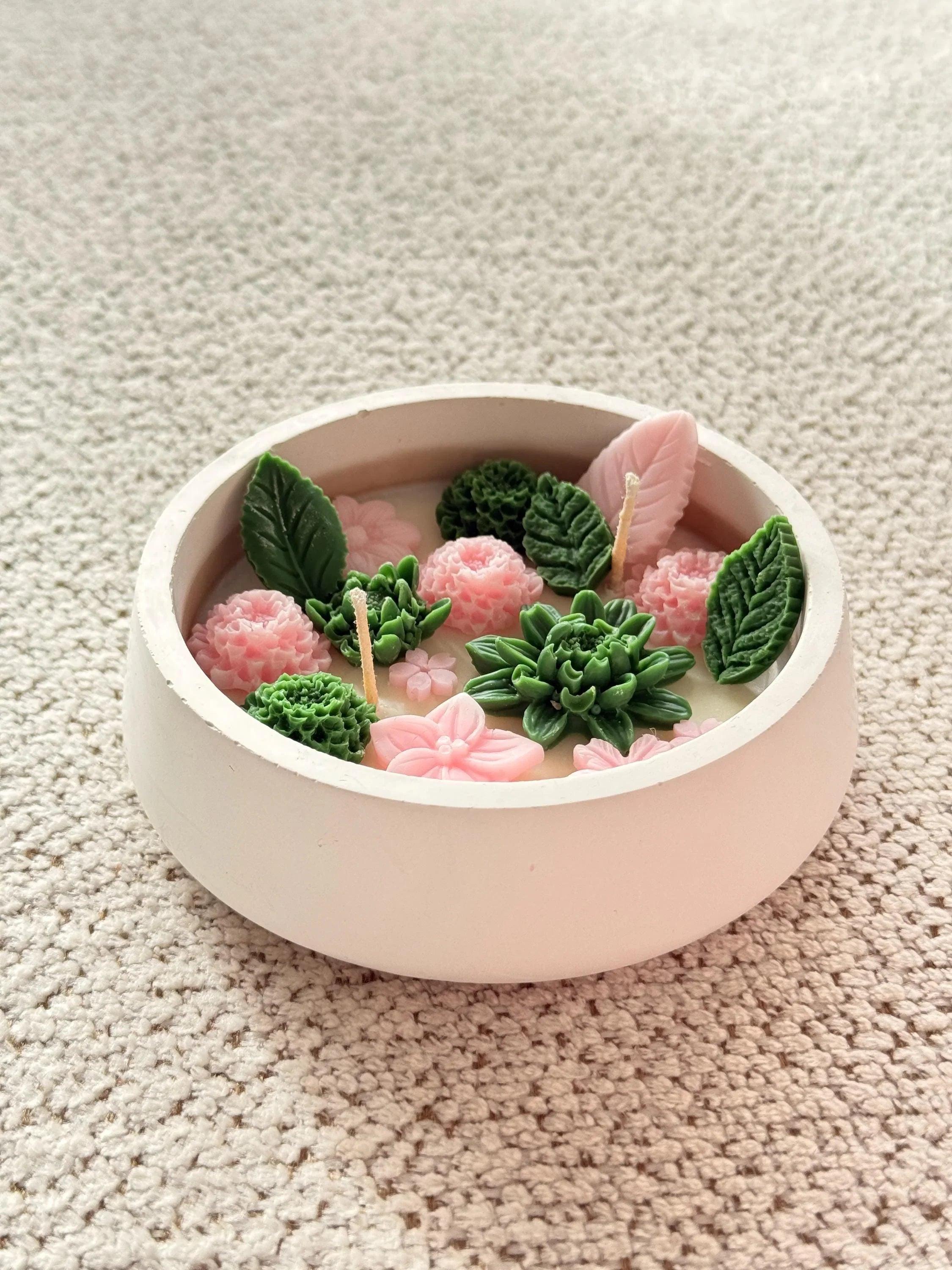Handmade soy candle with pink flowers and green succulents in a ceramic bowl, Scandinavian home decor