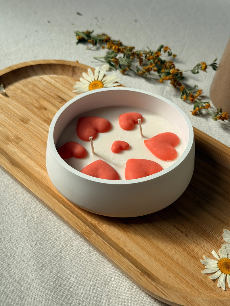 White soy candle with coral hearts in ceramic bowl, styled on wooden tray with dried flowers for cozy home décor