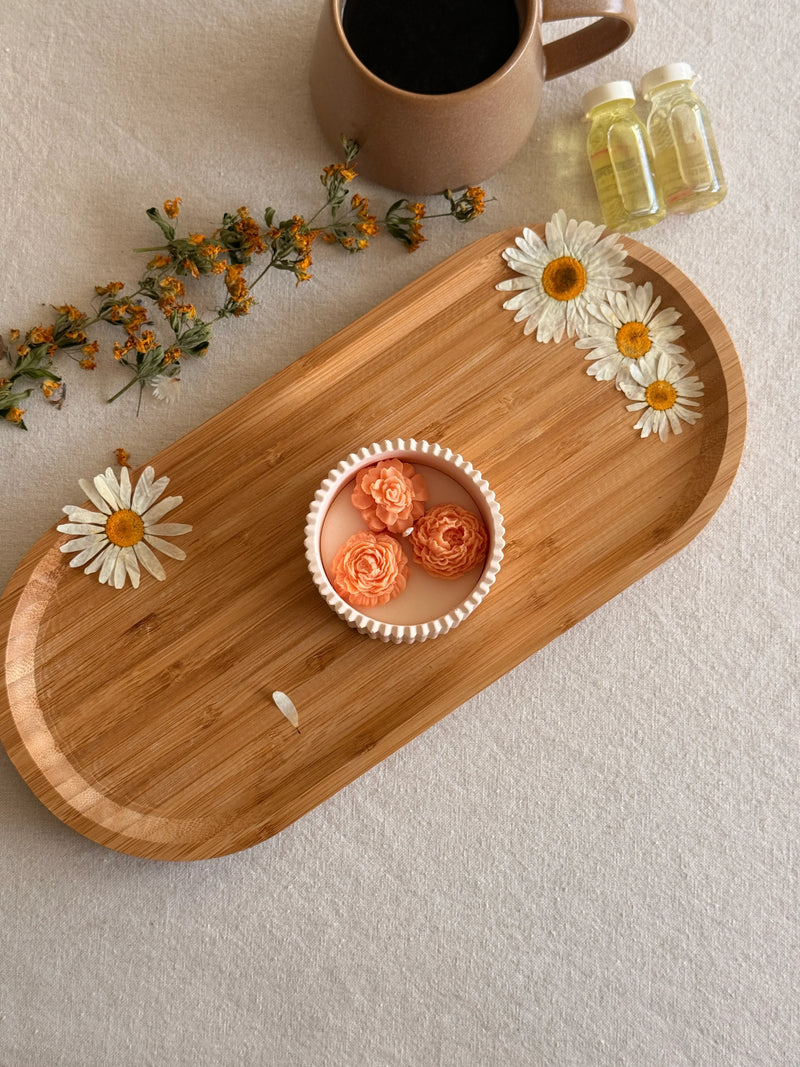Handmade soy candle with floral design on wooden tray, styled with dried daisies and coffee mug for cozy home décor