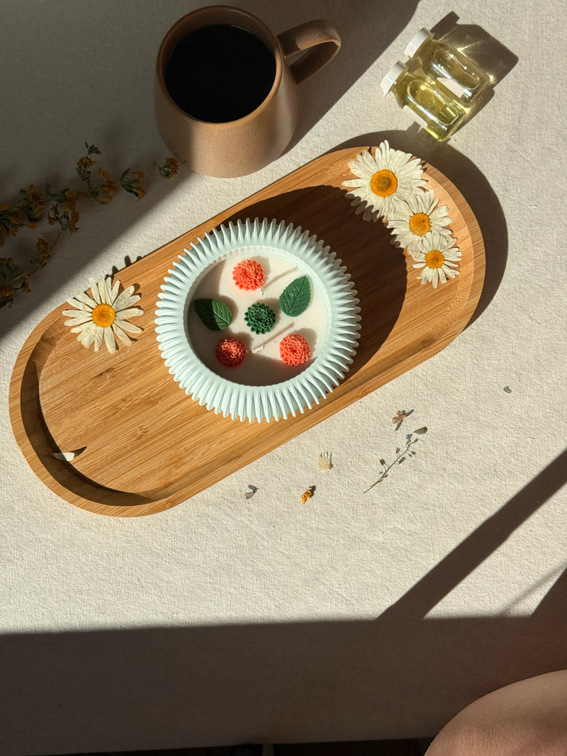 Handmade soy candle with floral design in mint bowl, styled with daisies and coffee on wooden tray for cozy home décor.