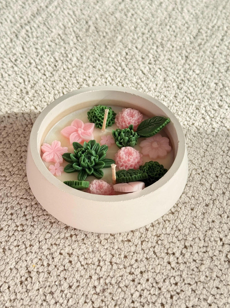 Handmade soy candle with pink flowers and green succulents in a white ceramic bowl, Scandinavian home decor