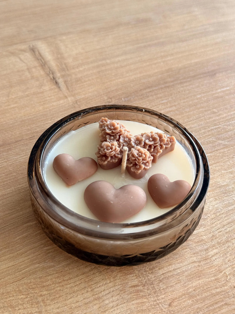 Handmade soy candle with heart and floral wax decorations in a glass jar