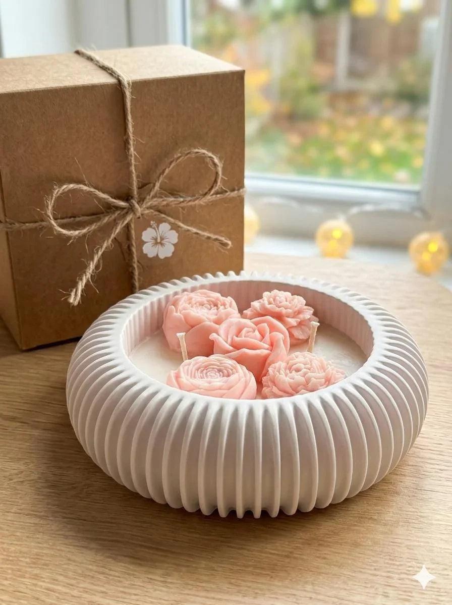 Handmade soy candle with pink rose blooms in white ceramic bowl, rustic gift box nearby, cozy home decor