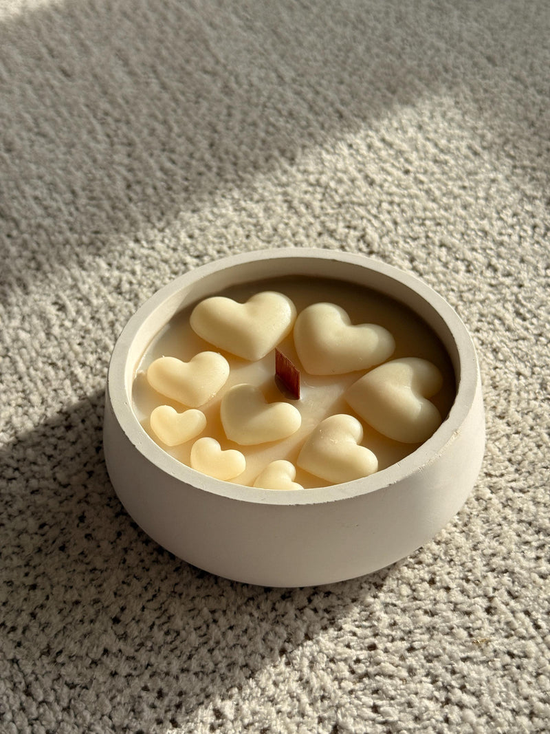 Handmade soy candle with heart-shaped wax melts in white ceramic bowl, cozy Scandinavian home decor