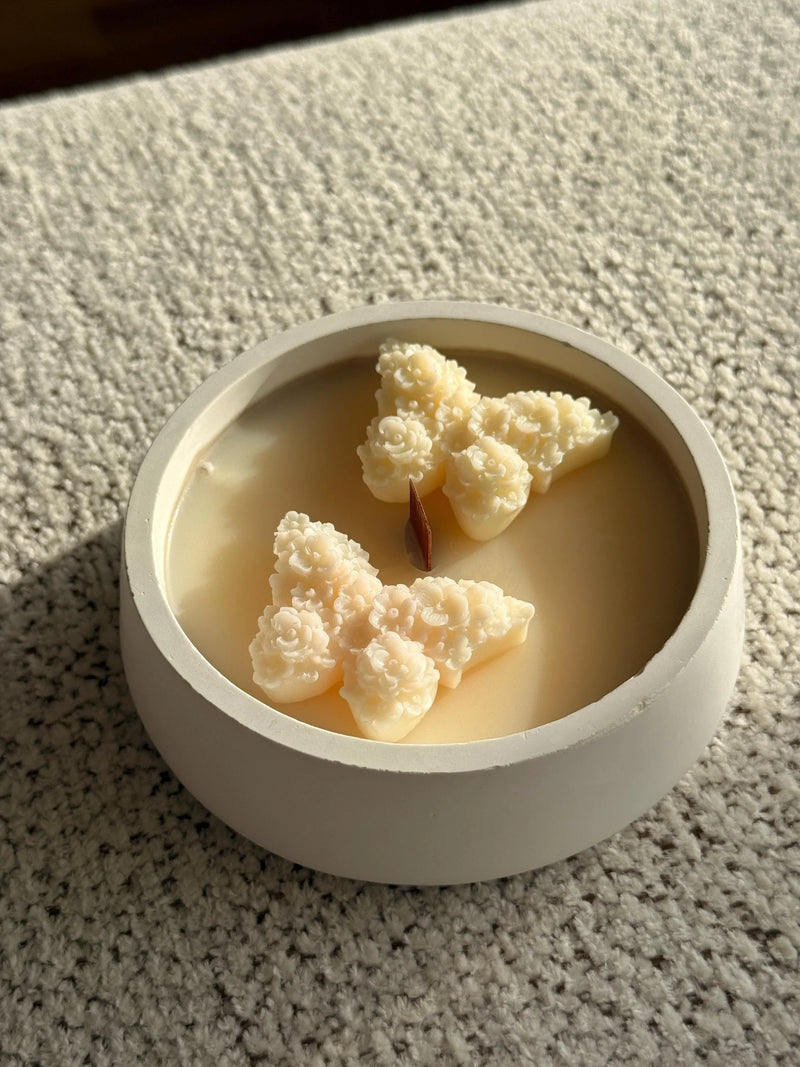 Handmade soy candle with floral wax art in a minimalist white ceramic bowl, perfect for cozy Scandinavian home décor.