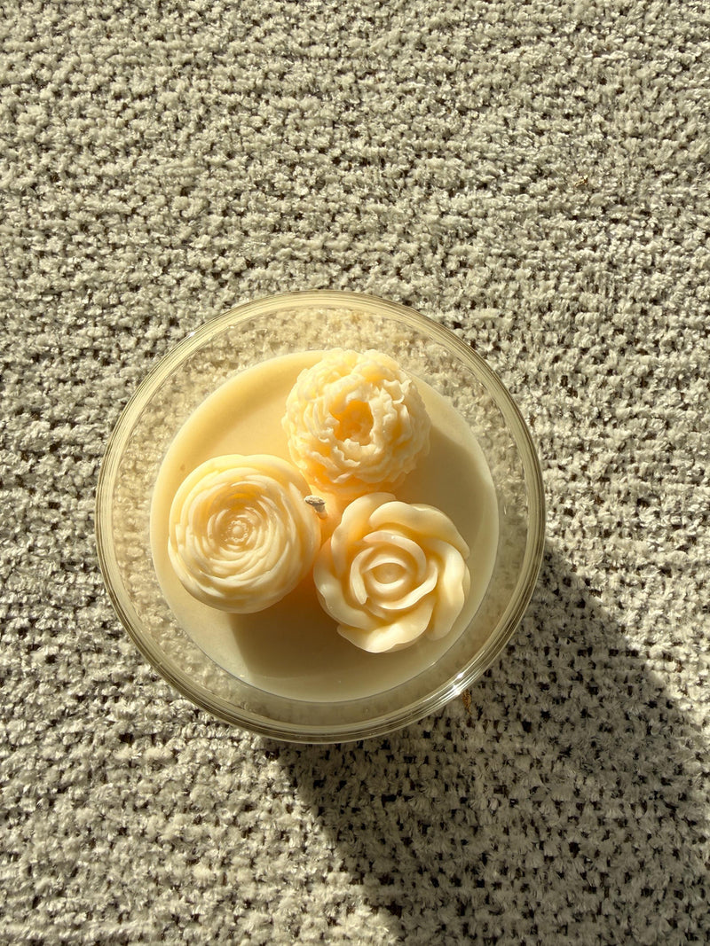 Handmade soy candle with three sculpted rose blooms in a clear glass jar, cozy Scandinavian home decor