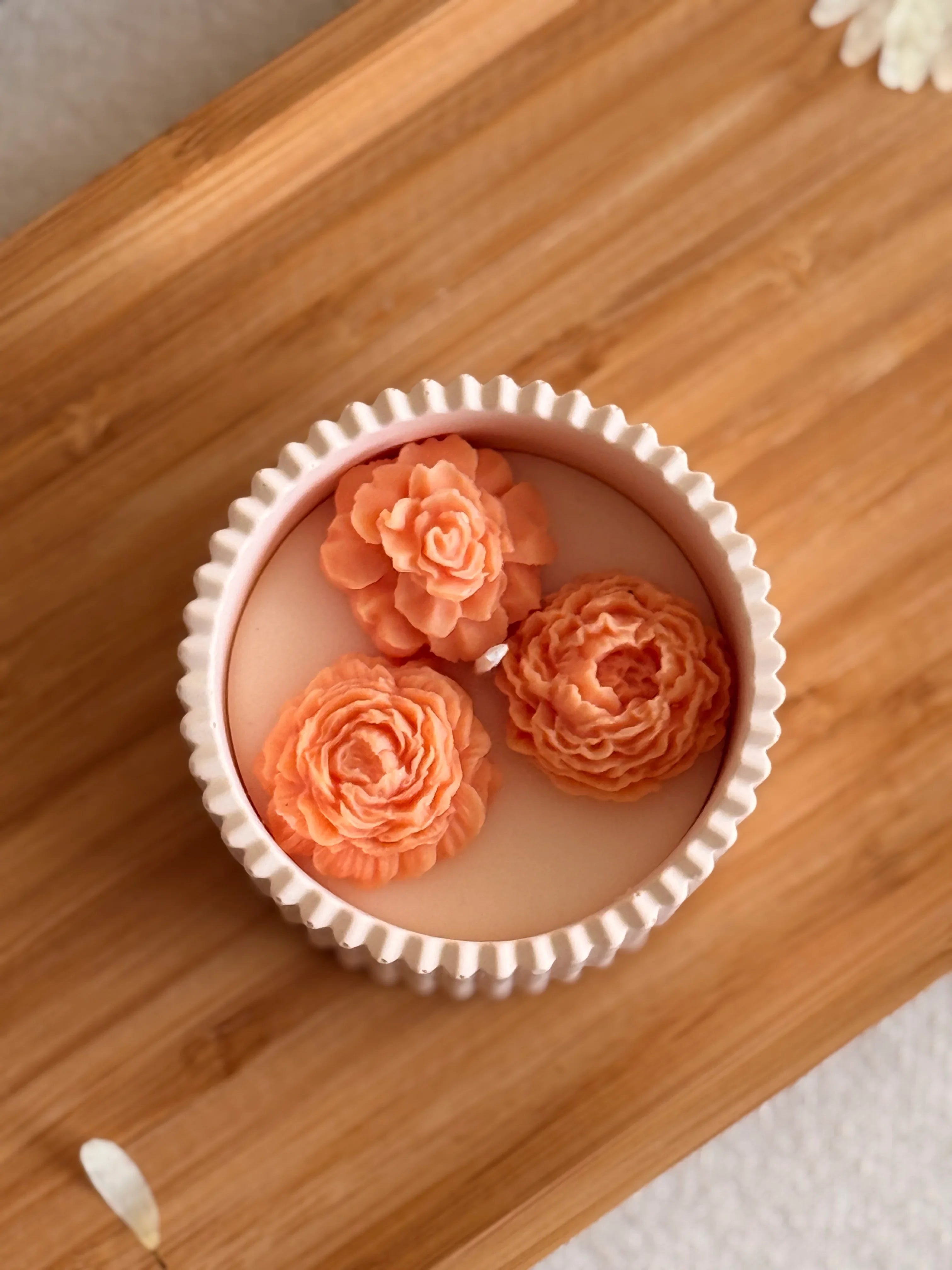 Handmade soy candle with peach rose decorations in a white ceramic dish, perfect for cozy home décor.