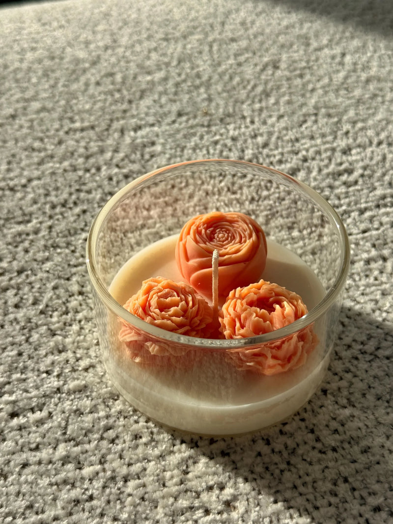 Handmade soy candle with three peach rose blooms in clear glass jar, cozy Scandinavian home décor