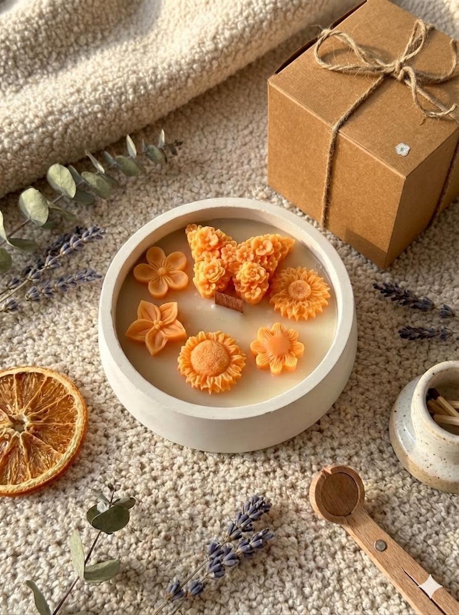 Handmade soy candle with orange flower wax melts, dried citrus, lavender, and gift box on cozy textured rug