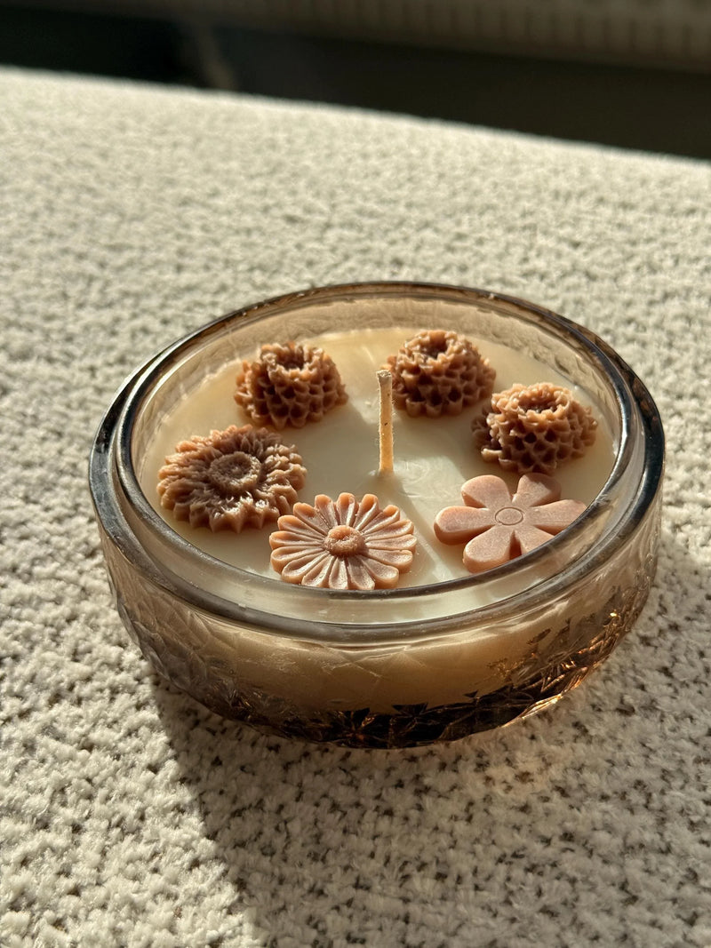 Handmade soy candle with floral wax decorations in a glass jar, perfect for cozy home décor.