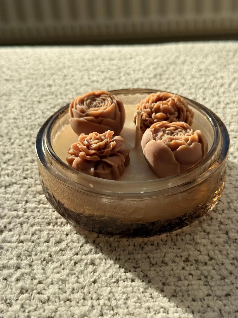 Handmade soy candle with rose-shaped wax blooms in a vintage glass jar, cozy home décor