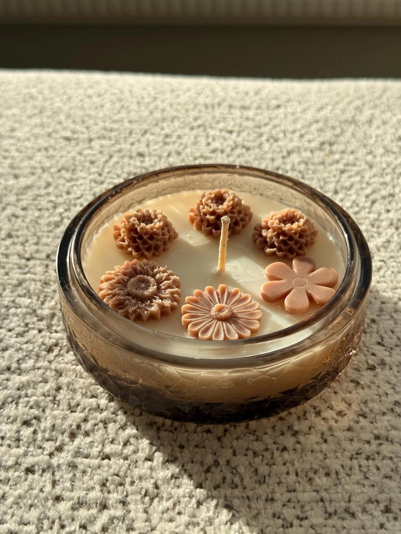 Handmade soy candle with floral wax decorations in a glass jar, cozy home decor