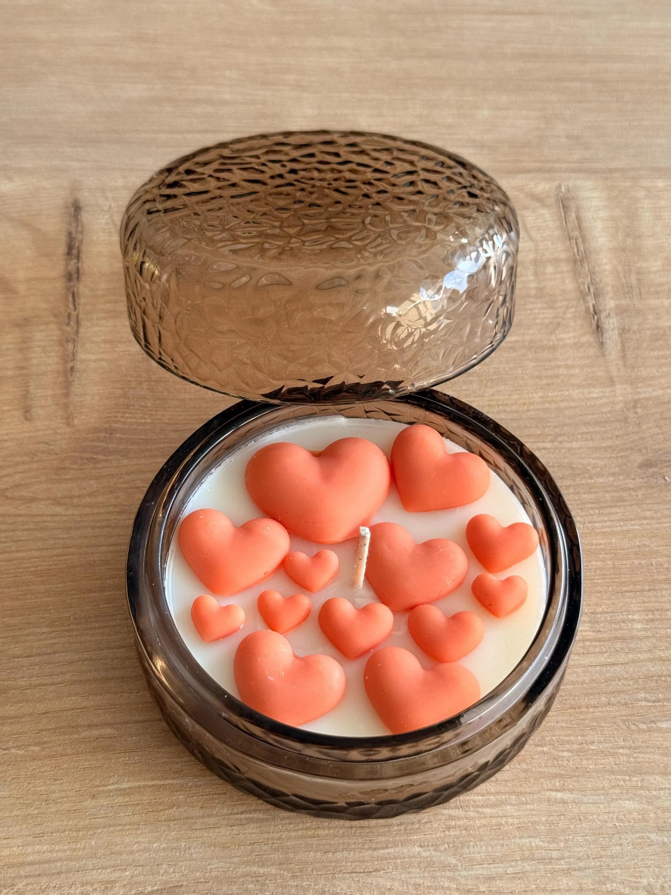 Handmade soy candle with coral heart decorations in a textured glass jar, perfect for cozy home décor or thoughtful gifts.