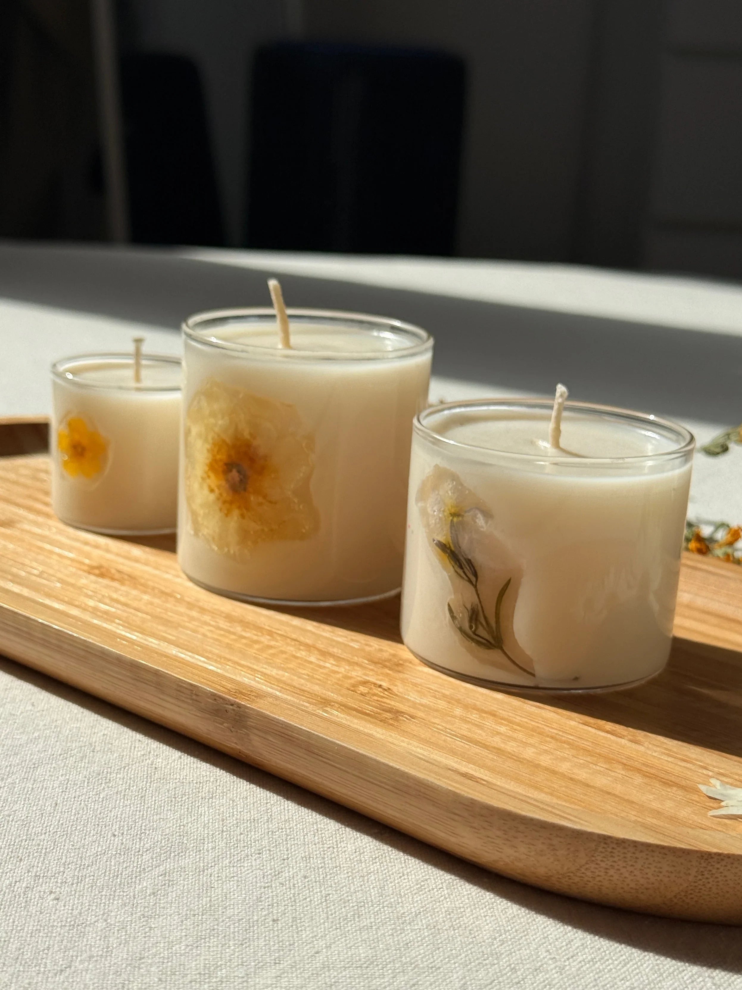 Handmade soy candles decorated with real dried flowers in clear glass jars, natural botanical Scandinavian home decor.