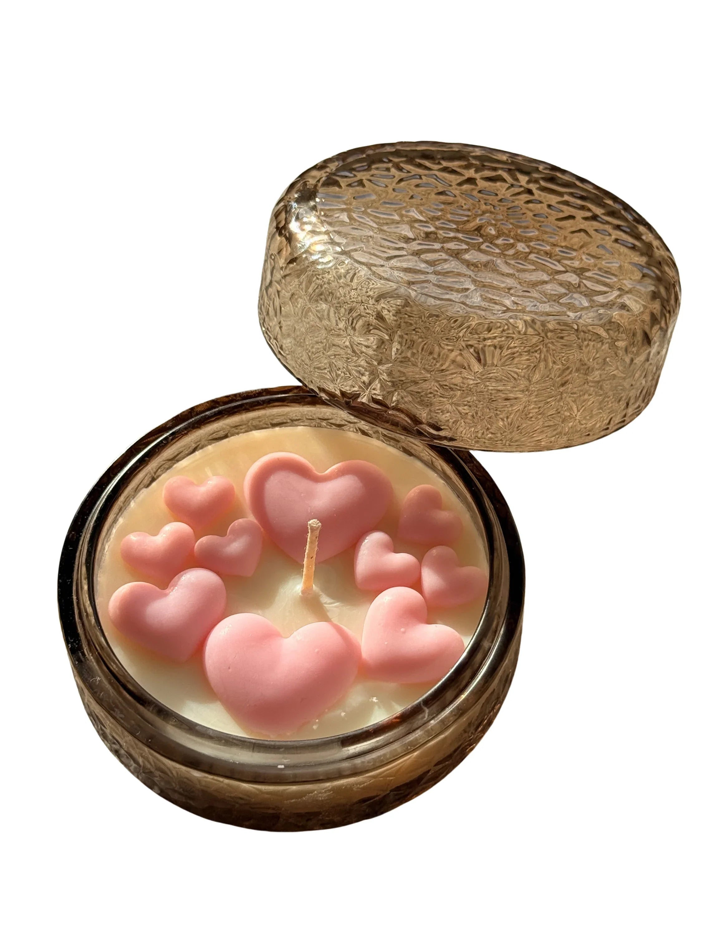 Handmade soy candle with pink heart decorations in a textured amber glass jar, perfect for cozy home décor.