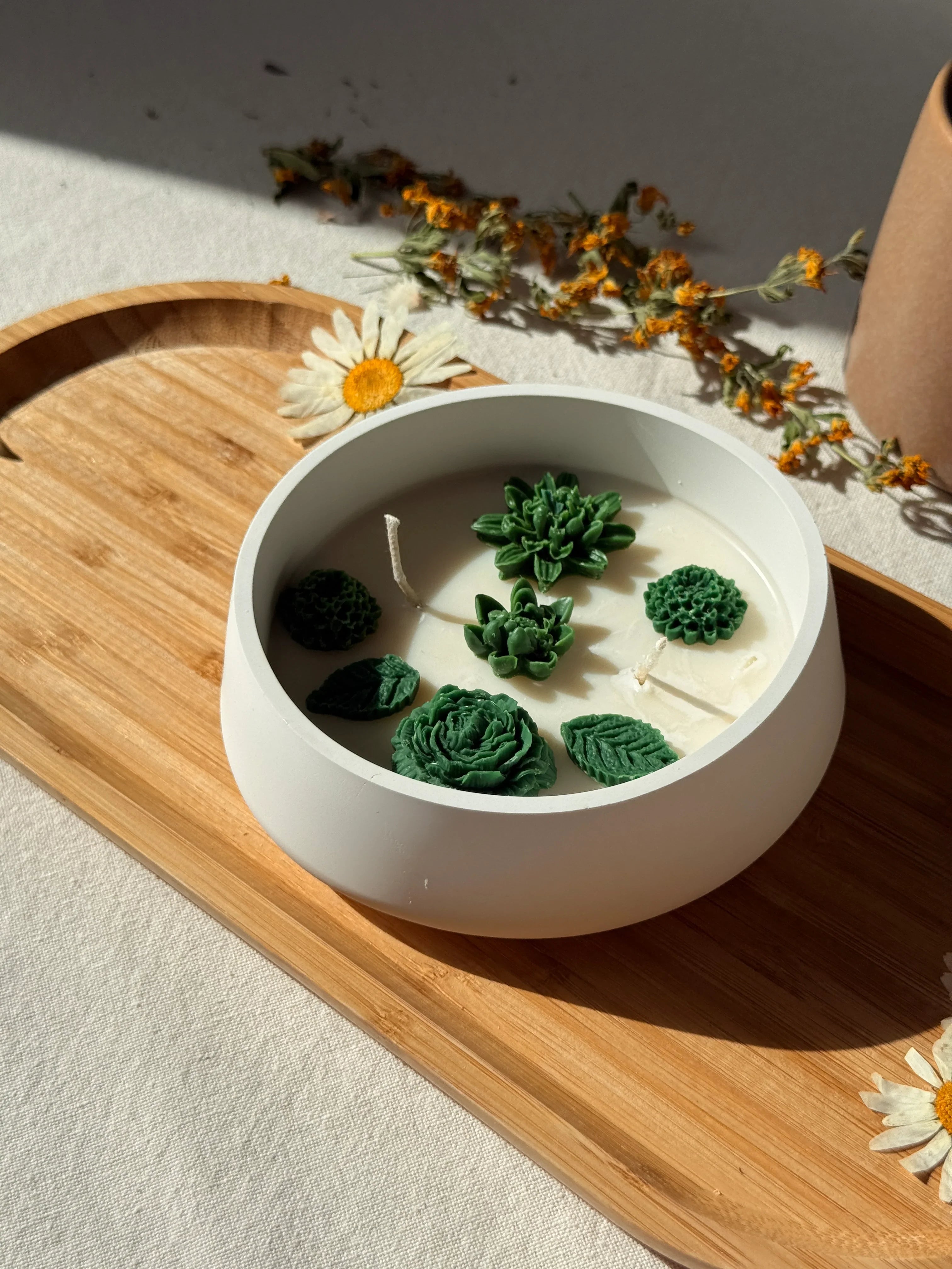 Handmade soy candle with green succulent wax decor, on wooden tray with dried flowers, Scandinavian home décor