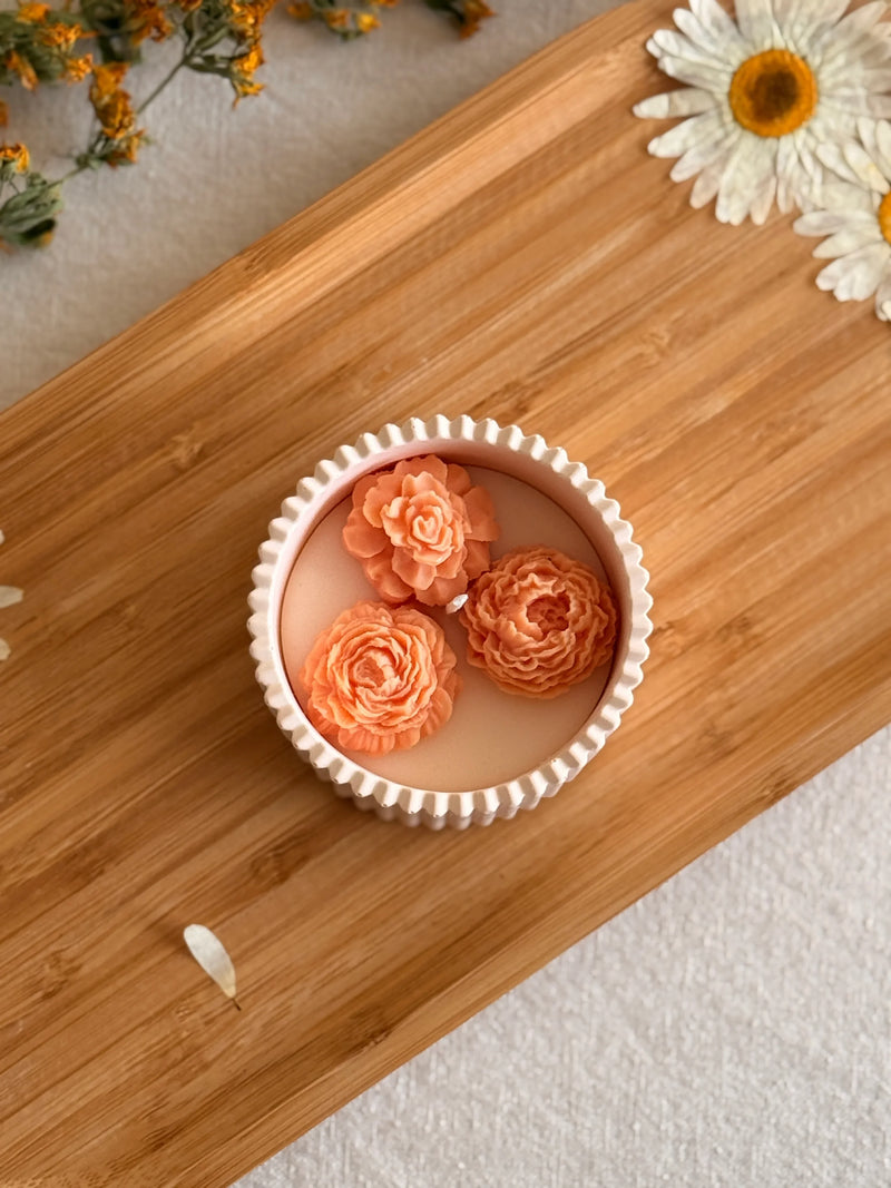 Handmade soy candle with 3 peach roses in white scalloped tin, styled on wood tray with dried flowers