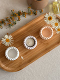 Handmade soy candles in rope-textured holders on wooden tray with dried daisies, Scandinavian home decor