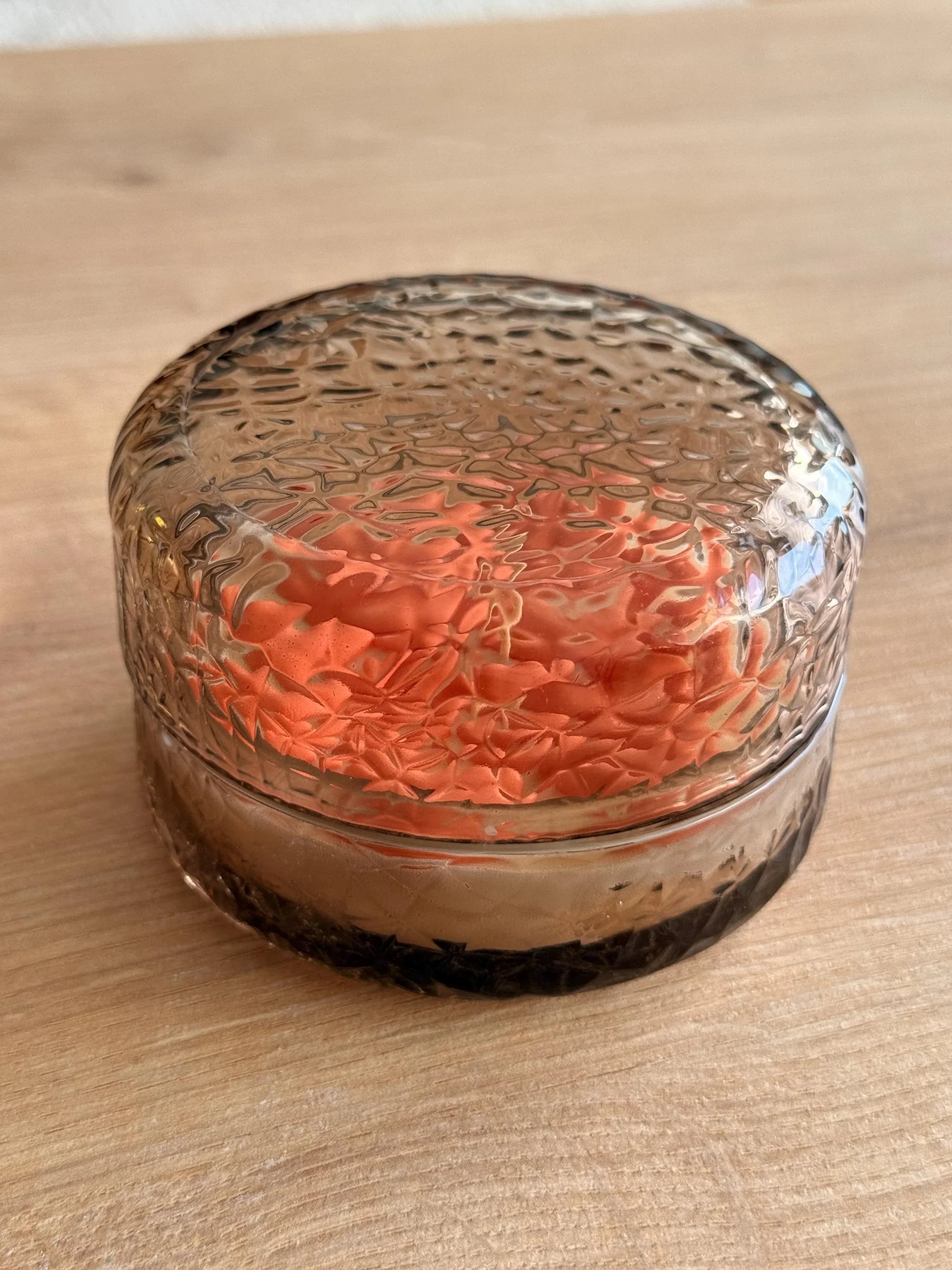 Handmade soy candle in textured glass jar with orange floral design, Scandinavian home décor