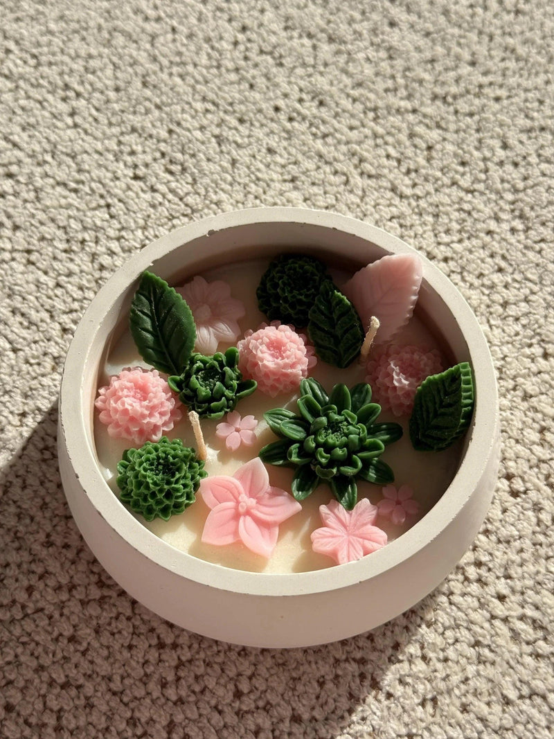Handmade soy candle with pink flowers and green succulents in a white ceramic bowl, Scandinavian home decor