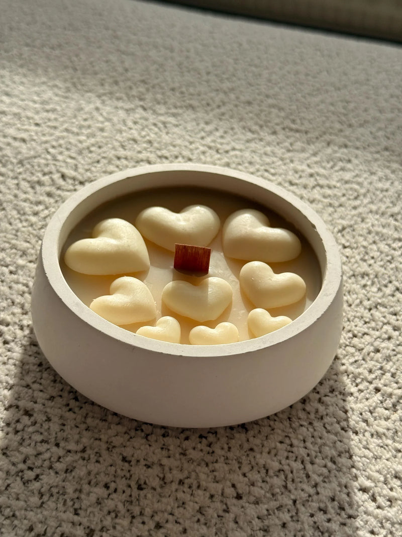 Handmade soy candle with heart-shaped wax and wooden wick in white ceramic bowl, cozy Scandinavian home decor