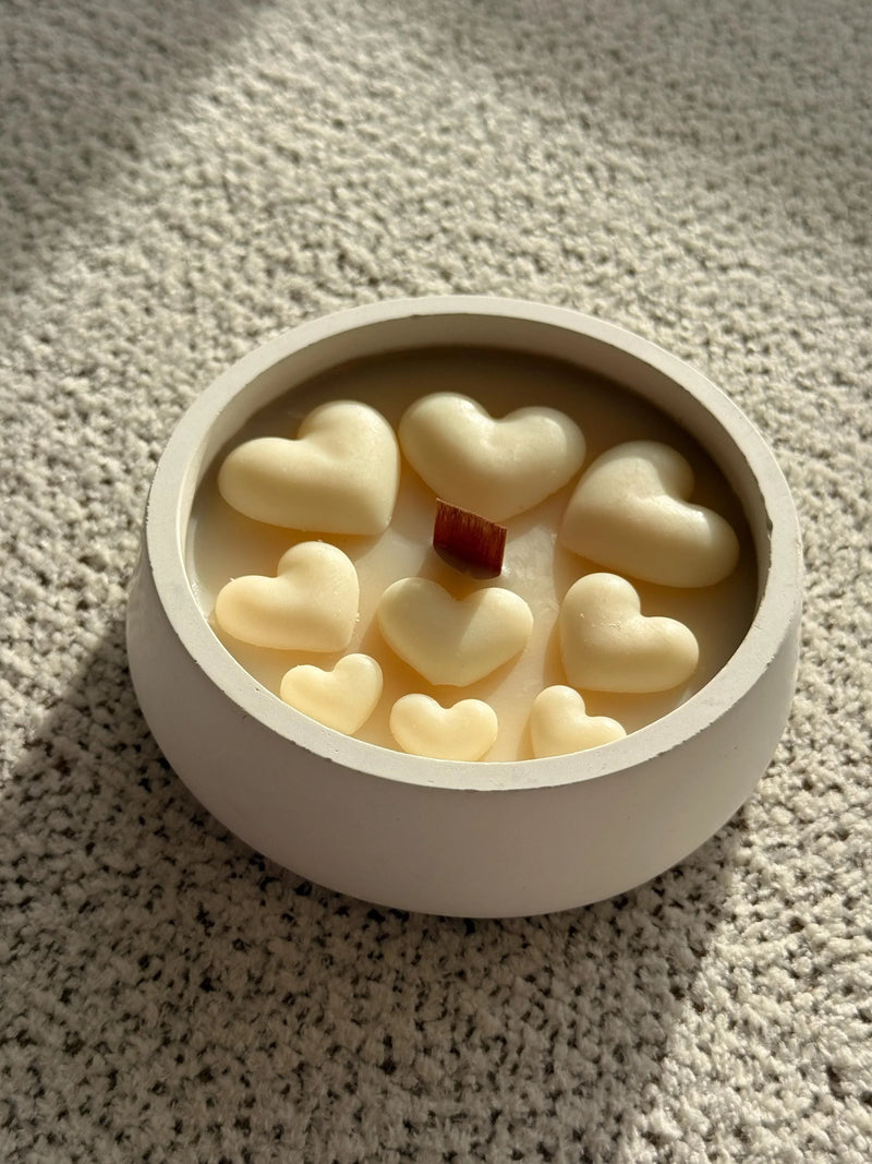 Handmade soy candle with heart-shaped wax melts and wooden wick in minimalist white container, cozy home decor