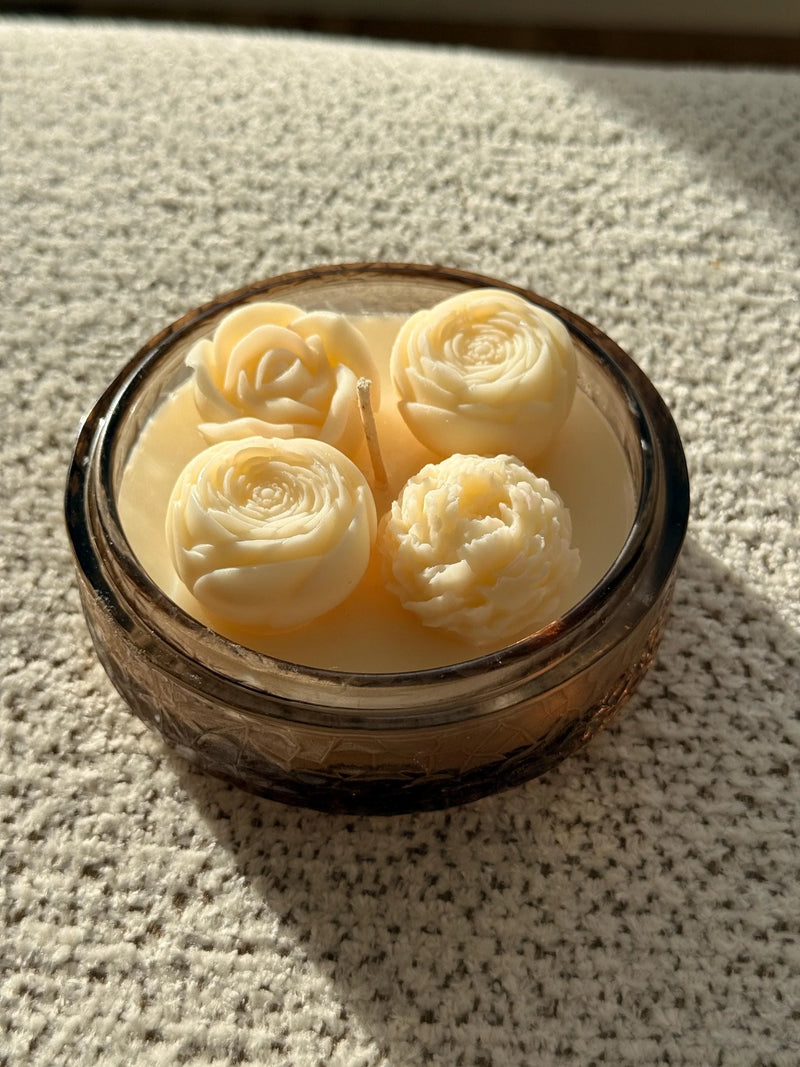 Handmade soy candle with rose-shaped wax blooms in amber glass jar, Scandinavian home decor