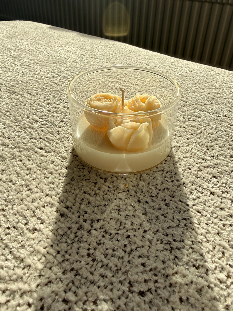 Handmade soy candle with sculpted cream roses in clear glass jar, cozy Scandinavian home decor